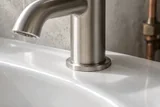 Illustration of a brushed-metal tap meeting a ceramic basin
