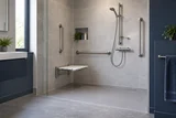 An accessible level-entry shower with sturdy grab rails, fold-down seat and reachable thermostatic controls
