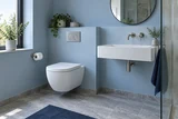 A newly fitted wall-hung toilet and brushed nickel wall-mounted basin spout in a carefully finished pale blue bathroom