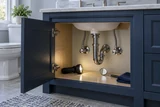 A bathroom vanity access door open for maintenance, a flashlight illuminating clean supply fittings and a small inspection mirror