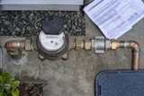 A municipal water meter assembly with a flow-limiting fitting and a folded conservation worksheet
